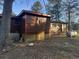 Exterior shot of the home showing the backyard, brown siding, and white painted cinder block foundation at 144 Flat Rock Rd, Oxford, GA 30054