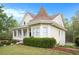 Charming yellow two-story home featuring a manicured lawn, front porch, and unique architectural details at 5732 Falls View Dr, Buford, GA 30518