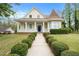 Charming yellow two-story home featuring a manicured lawn, front porch, and unique architectural details at 5732 Falls View Dr, Buford, GA 30518