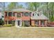 Charming two-story brick home with black shutters and a well-manicured front lawn surrounded by mature trees at 1010 Allenbrook Ln, Roswell, GA 30075