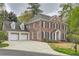 Stately brick home featuring a two-car garage, long driveway, and lush green landscaping around the property at 4503 Payton Oaks Ne Pl, Atlanta, GA 30345