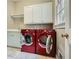 Well-lit laundry room featuring red washer and dryer, white cabinets, and utility sink at 4503 Payton Oaks Ne Pl, Atlanta, GA 30345