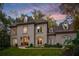 Charming two-story home with manicured lawn, mature trees, and a colorful sunset sky at 302 Rolling Rock Se Rd, Marietta, GA 30067