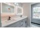 Updated bathroom features gray vanity with double sinks, modern faucets, and square illuminated mirrors at 5254 Greenpoint Dr, Stone Mountain, GA 30088