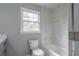 Bathroom featuring a white tiled tub and shower, a toilet, and a window at 5254 Greenpoint Dr, Stone Mountain, GA 30088