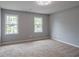 Bright, carpeted bedroom with two windows, neutral paint, and a modern light fixture at 5254 Greenpoint Dr, Stone Mountain, GA 30088