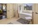 Bright bathroom features a soaking tub under a window and neutral tile at 6025 Golf View Xing, Locust Grove, GA 30248