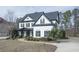 Beautiful two-story home featuring manicured landscaping, a curved walkway, and classic black and white design elements at 6025 Golf View Xing, Locust Grove, GA 30248