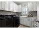The laundry room featuring cabinets, granite countertops, a sink, and black appliances at 1344 Chipmunk Forest Chase, Powder Springs, GA 30127