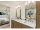 This bathroom features double sinks, granite countertops, and gold-trimmed mirrors with a bedroom through a doorway in the background at 3805 Cloudland Se Dr, Smyrna, GA 30082