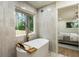 Stylish bathroom featuring a modern tub with wood accents, a garden view, and neutral tile at 3805 Cloudland Se Dr, Smyrna, GA 30082