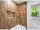 Modern bathroom with tiled walls, recessed shelf, and a bathtub with a window view at 3805 Cloudland Se Dr, Smyrna, GA 30082