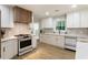 Well-lit kitchen features white cabinets, stainless steel appliances, modern fixtures and a view of the backyard at 3805 Cloudland Se Dr, Smyrna, GA 30082