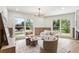Bright living room with a modern chandelier, wood trim accent wall, and large windows showcasing yard at 3805 Cloudland Se Dr, Smyrna, GA 30082