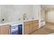 Elegant wet bar featuring white tile backsplash, modern cabinets, gold fixtures, and beverage fridge at 3805 Cloudland Se Dr, Smyrna, GA 30082