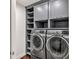 Modern laundry room with gray cabinets, open shelving, and stainless steel washer and dryer at 2739 Springfount Trl, Lawrenceville, GA 30043