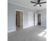 Open bedroom featuring ceiling fan, gray carpet, and access to bathroom and hallway at 3068 Turning Creek Trail, Dacula, GA 30019
