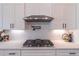 Close up of a modern kitchen featuring stainless steel range hood, white subway tiles, and white cabinetry at 3068 Turning Creek Trail, Dacula, GA 30019