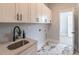 Bright laundry room with white cabinets, black hardware, quartz counters, and stylish marble pattern floor at 3068 Turning Creek Trail, Dacula, GA 30019