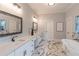 Luxurious bathroom with dual sinks, elegant counters, large framed mirror and marble tile floors at 3068 Turning Creek Trail, Dacula, GA 30019