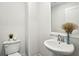 Modern half bath with a white pedestal sink, a stylish mirror, and a low-flow toilet at 2310 Portrush Se Way, Atlanta, GA 30339