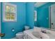 Bathroom features a toilet, sink, and mirror against blue walls with a window at 3420 Sweetbriar Ln, Powder Springs, GA 30127