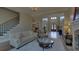 Spacious living room with hardwood floors, tufted sofa, and a staircase leading to the second floor at 5224 Brendlynn Dr, Suwanee, GA 30024