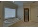 Bright main bathroom with a jacuzzi tub, a separate glass-enclosed shower, and a large window at 5224 Brendlynn Dr, Suwanee, GA 30024