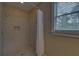 Shower stall with tile surround, window, shower head, and shampoo nook at 5224 Brendlynn Dr, Suwanee, GA 30024