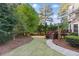 Manicured backyard with lush green grass, landscaping, and a small deck in the trees at 700 Henley Fields Cir, Johns Creek, GA 30097
