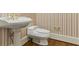 Classic powder room with white fixtures, gold faucet, and striped wallpaper at 700 Henley Fields Cir, Johns Creek, GA 30097