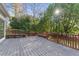 Large gray deck with wood railings and bench seating surrounded by mature trees at 700 Henley Fields Cir, Johns Creek, GA 30097