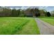 Picturesque view of a long driveway leading to a home surrounded by a vast green field at 2210 Holly Springs Rd, Rockmart, GA 30153