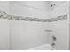 Close-up of bathtub/shower combo with white subway tile and decorative mosaic tile accent at 4522 Willow Oak Trl, Powder Springs, GA 30127
