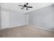 A large bedroom with neutral walls and carpet, featuring a ceiling fan and two entry doors at 4522 Willow Oak Trl, Powder Springs, GA 30127