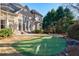 Beautiful backyard with a manicured lawn, putting green, and view of the elegant brick home at 2281 Bransley Pl, Duluth, GA 30097