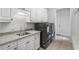 Spacious laundry room with utility sink, granite counters, white cabinetry, and gray washer and dryer units at 2281 Bransley Pl, Duluth, GA 30097