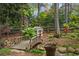 Backyard garden with a wooden bridge over a small stream and a charming playhouse at 4688 Oakleigh Manor Dr, Powder Springs, GA 30127