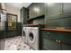 Spacious laundry room with green custom cabinets, modern appliances, and stylish tile floors at 4688 Oakleigh Manor Dr, Powder Springs, GA 30127