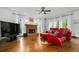 Inviting living room with a red sofa, cozy fireplace, large windows, and ceiling fan at 4688 Oakleigh Manor Dr, Powder Springs, GA 30127