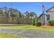 Home exterior featuring an American flag, green lawn, long driveway, and partially fenced perimeter at 6585 Queen Mill Se Rd, Mableton, GA 30126
