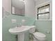 Charming bathroom featuring a pedestal sink, toilet, and window providing natural light at 4606 Greensprings Rd, College Park, GA 30337