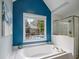 Bright bathroom featuring soaking tub, blue accent wall, and tiled shower at 5296 Camden Lake Nw Pkwy, Acworth, GA 30101