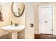 Elegant powder room featuring a pedestal sink, framed mirror, and classic paneled door at 7497 Treehouse Ct, Douglasville, GA 30135