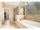 Bright bathroom featuring a soaking tub, shower, and large window bringing the outside in at 7497 Treehouse Ct, Douglasville, GA 30135