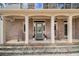 Inviting front porch with rocking chairs, neutral brick, stone accents, and a meticulously maintained facade at 7497 Treehouse Ct, Douglasville, GA 30135