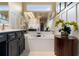 Bright bathroom featuring a soaking tub, vanity with storage, and a large mirror reflecting the elegant interior at 2630 Milford Ln, Alpharetta, GA 30009