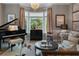 Cozy living room features a grand piano, bay window, chandelier, and neutral color palette at 2630 Milford Ln, Alpharetta, GA 30009