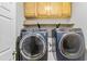 Modern laundry room with two front-load washer and dryer units, shelving, and storage cabinets at 5775 Stephens Mill Dr, Sugar Hill, GA 30518
