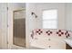 Bathroom with a shower and tub combination, decorative tile and window for natural light at 1218 Cabots Ln, Auburn, GA 30011